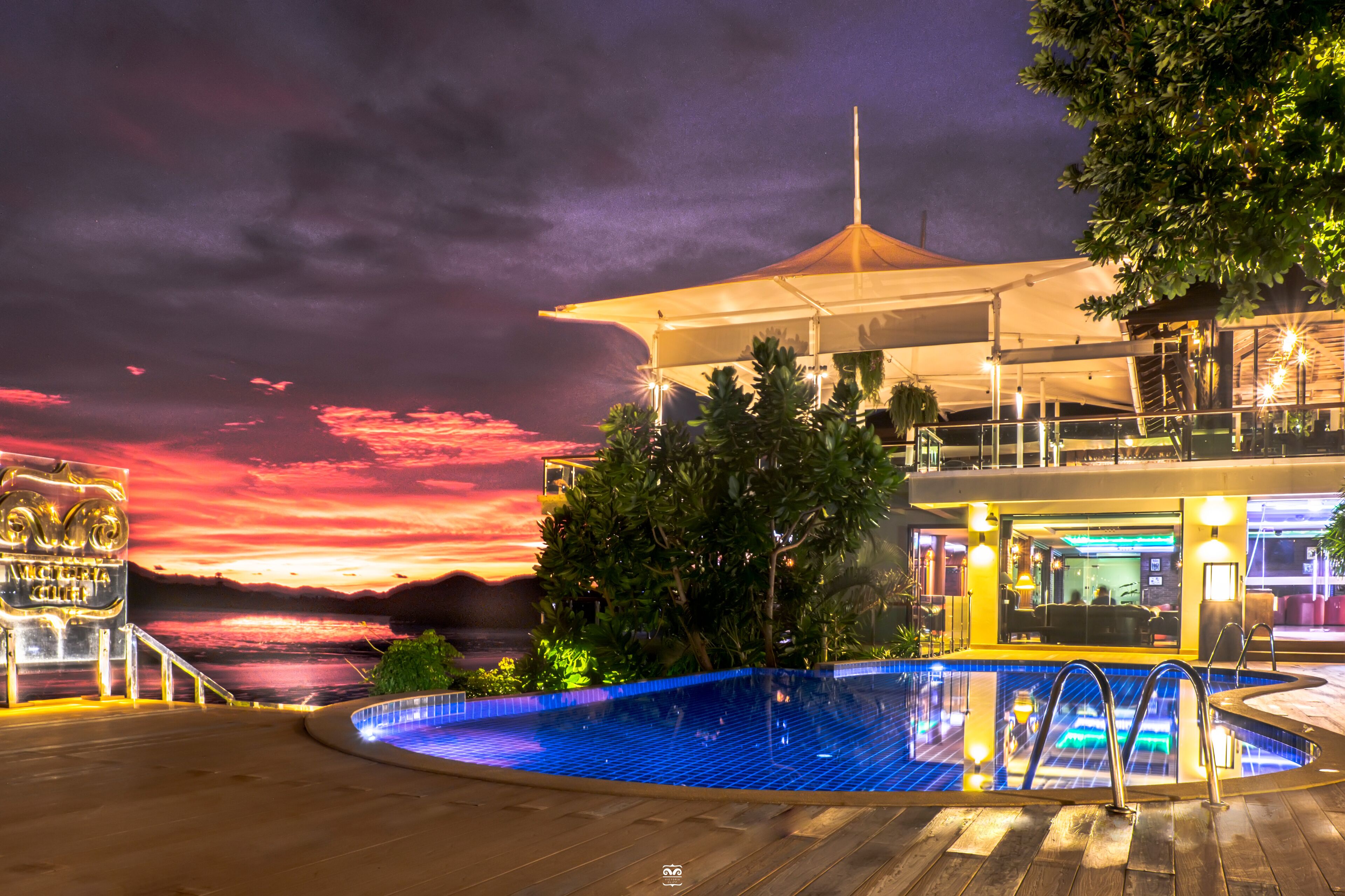 A pool area with a sunset view, a covered seating area, and a bar/lounge with outdoor seating.