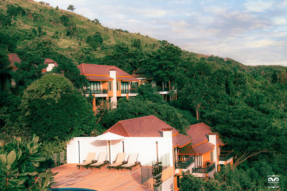A hillside property with multiple houses, a swimming pool, and lush greenery.