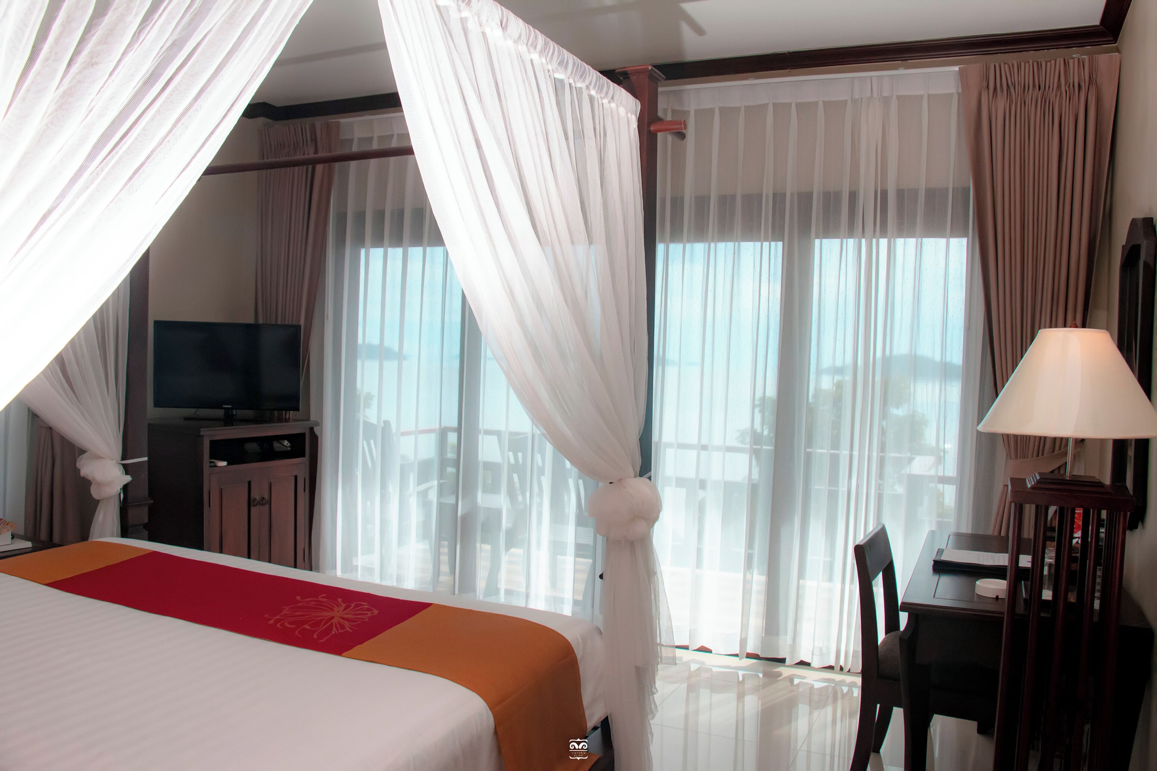 A hotel room with a bed, a television, a desk, and a chair.
