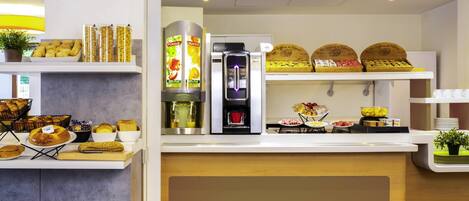 A breakfast buffet with various food items, a coffee machine, and a juice dispenser.