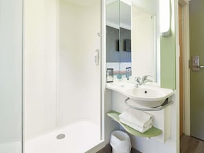 Ein modernes Badezimmer mit Dusche, Waschbecken und Spiegel.