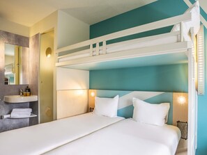 A bunk bed with a headboard, a bedside table with a lamp, and a mirror. - ibis budget Haguenau (Haguenau)
