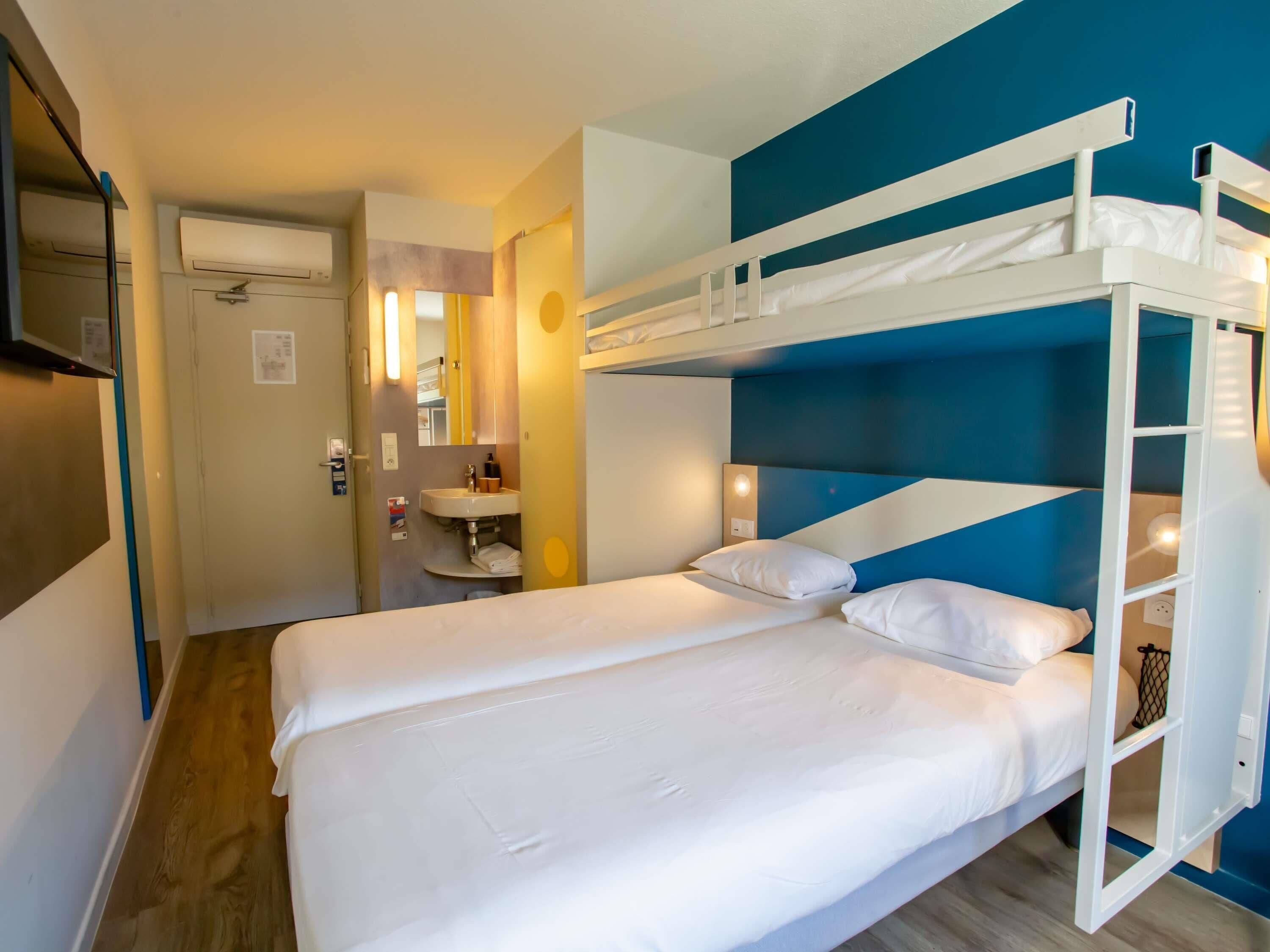 A bunk bed room with a mirror, sink, and wooden flooring.