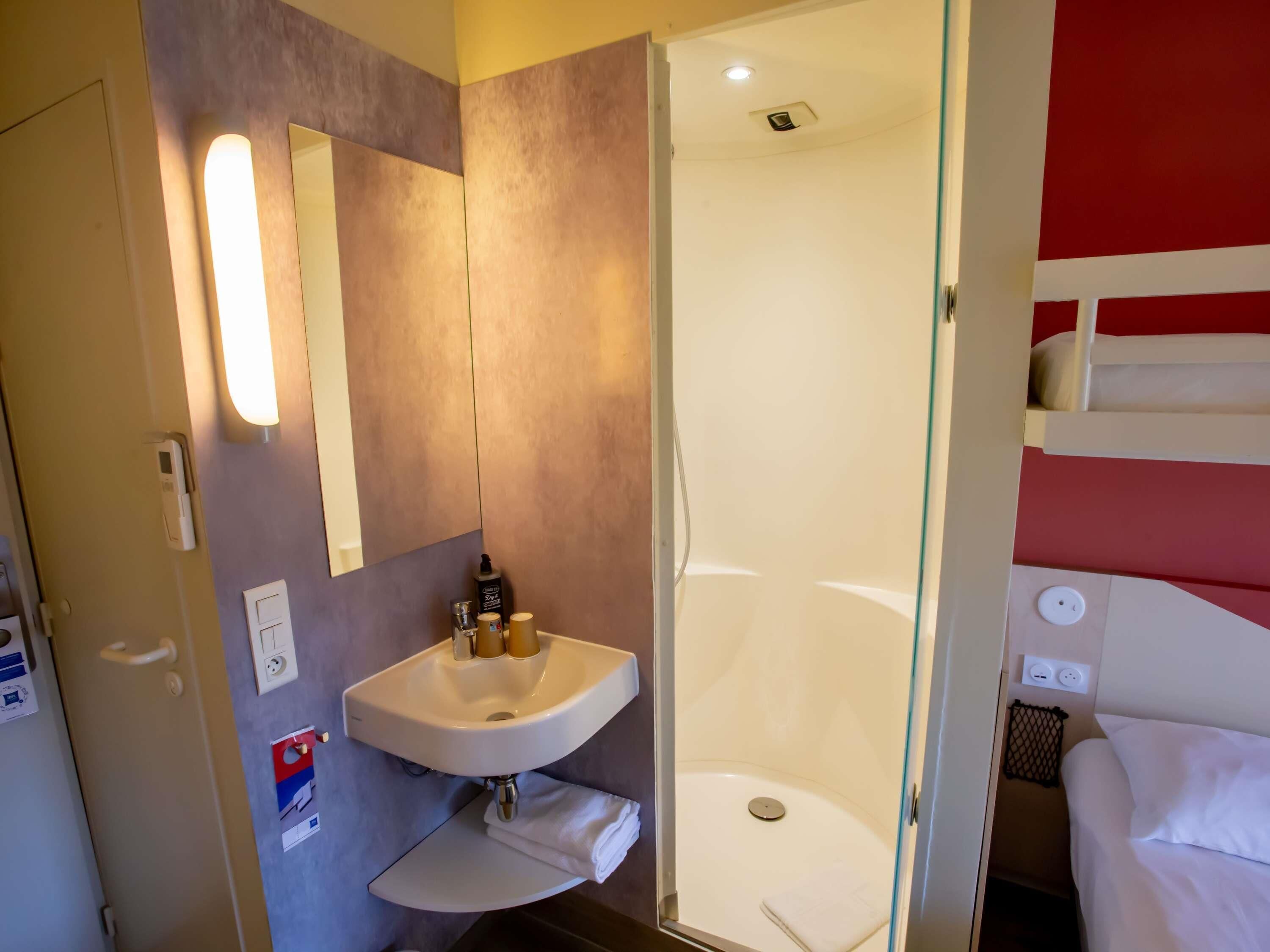 Een moderne badkamer met een wastafel, spiegel en douche.