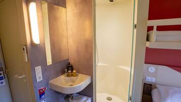 Een moderne badkamer met een wastafel, spiegel en douche.
