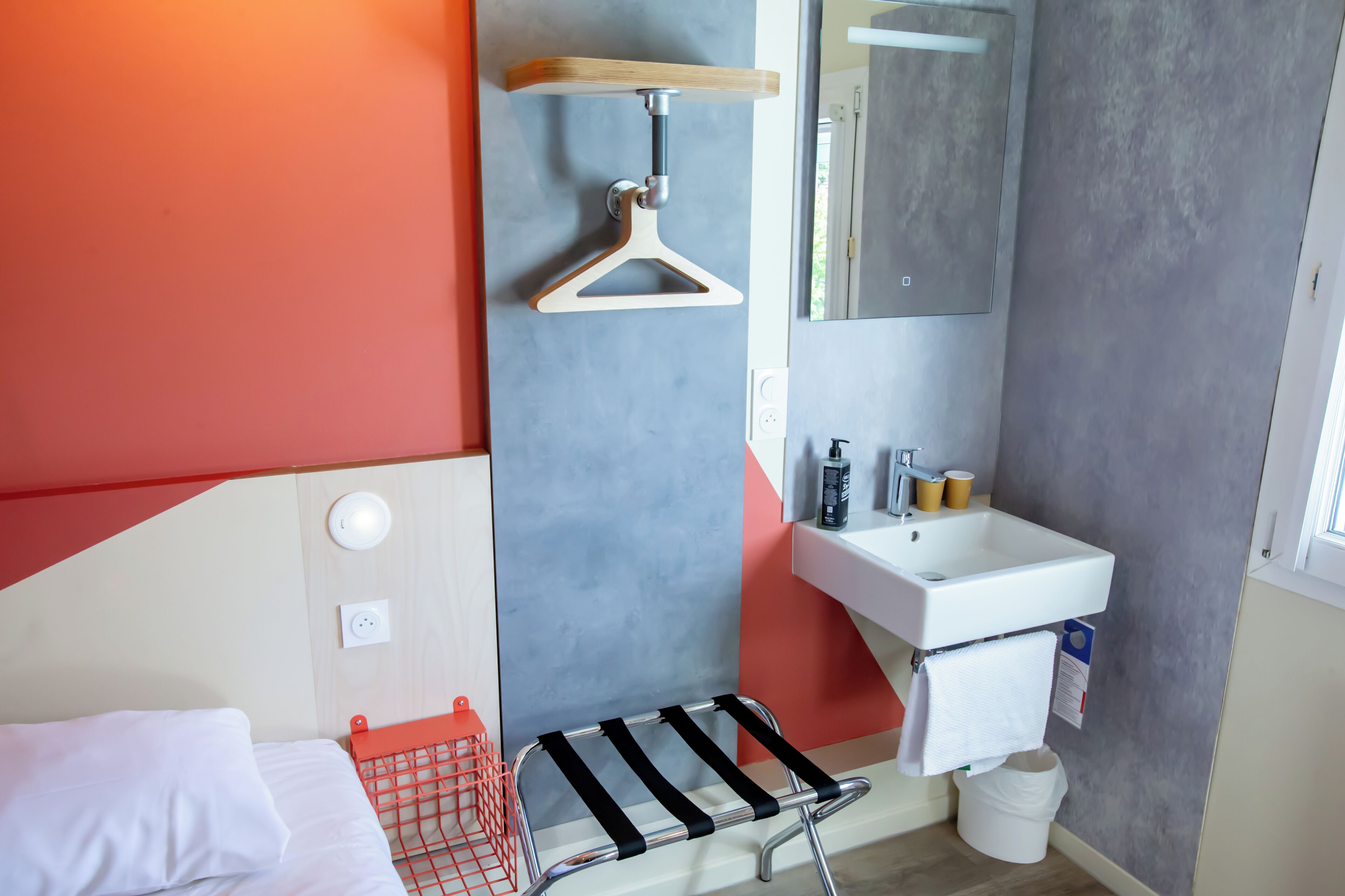 Un baño moderno con cama, ducha colgante, lavamanos y espejo.