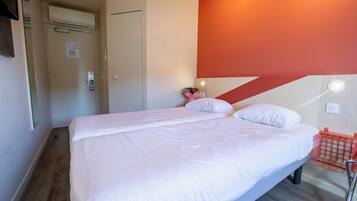 A bedroom with a bed, a wall-mounted light, and a red basket.