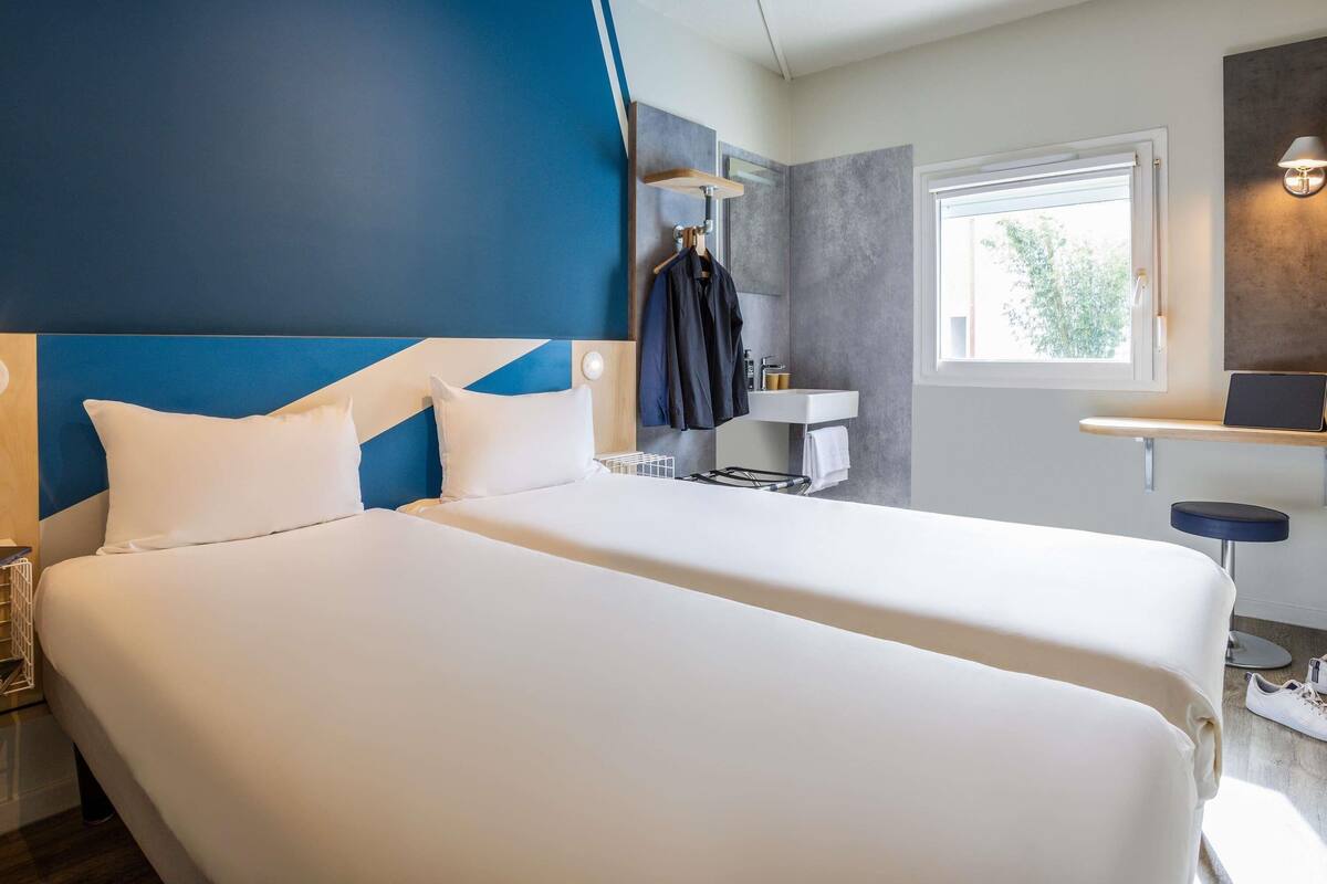 Ein Hotelzimmer mit zwei Betten, einem Badezimmer und einem Fenster.
