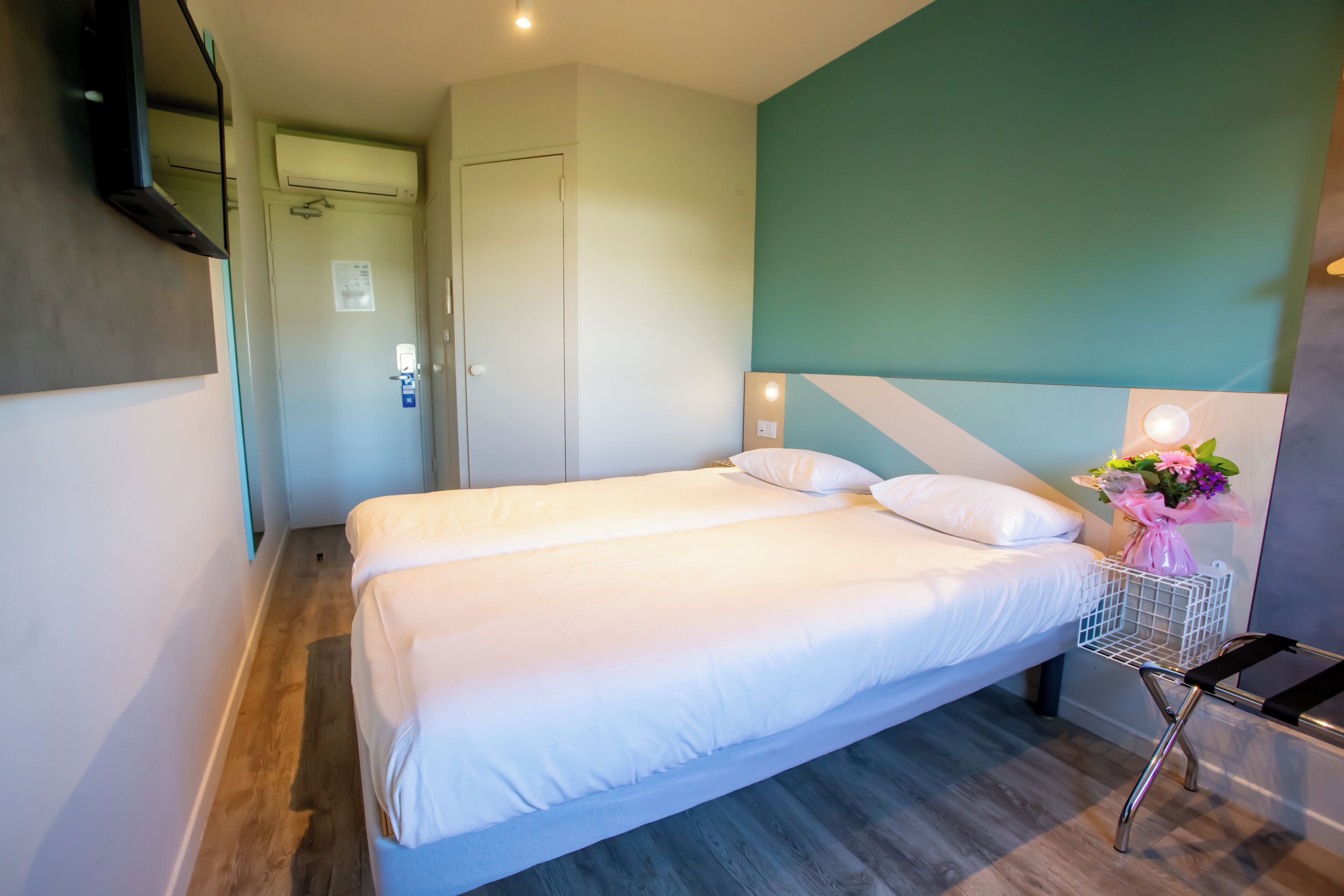 Una camera d'albergo con un letto, una scrivania e una TV a parete.