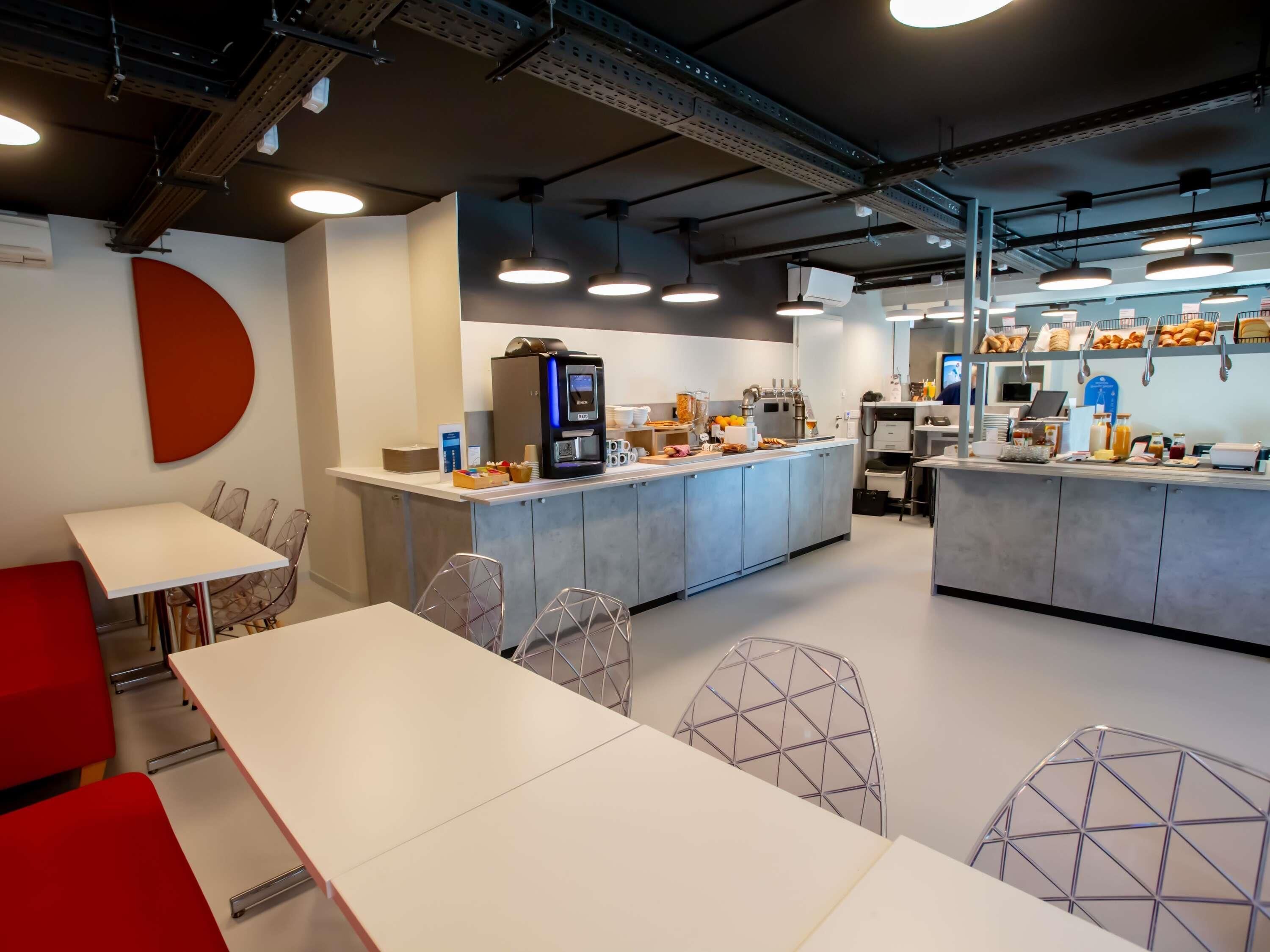 A modern cafe with a central counter, seating area, and a visible coffee machine.
