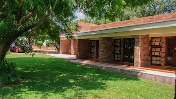 A brick building with a covered porch and a grassy lawn.