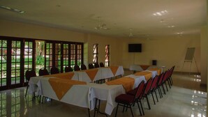 A conference room with long tables, chairs, and a projector screen. - Matilinda Lodge (Bulawayo)