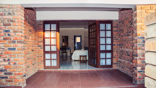 A room with a bed, a desk, and a chair. - Matilinda Lodge (Bulawayo)