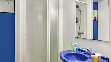 A bathroom with a shower, a sink with a blue countertop, and a mirror above the sink.