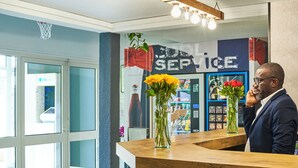 Una mesa de recepción con un florero de flores amarillas, un letrero que dice 'Cool Service' y una vista del interior que incluye un mostrador y una exhibición de artículos.