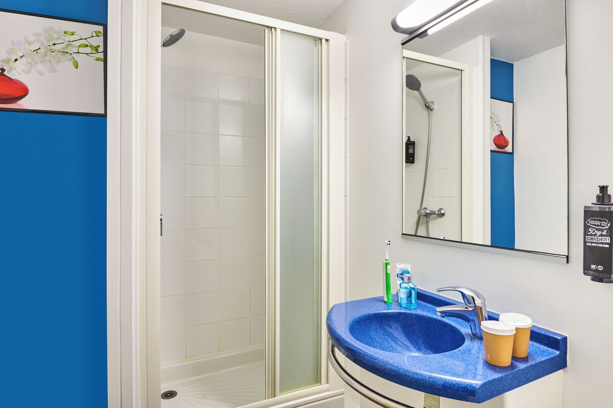 A bathroom with a blue sink, a mirror, and a shower.