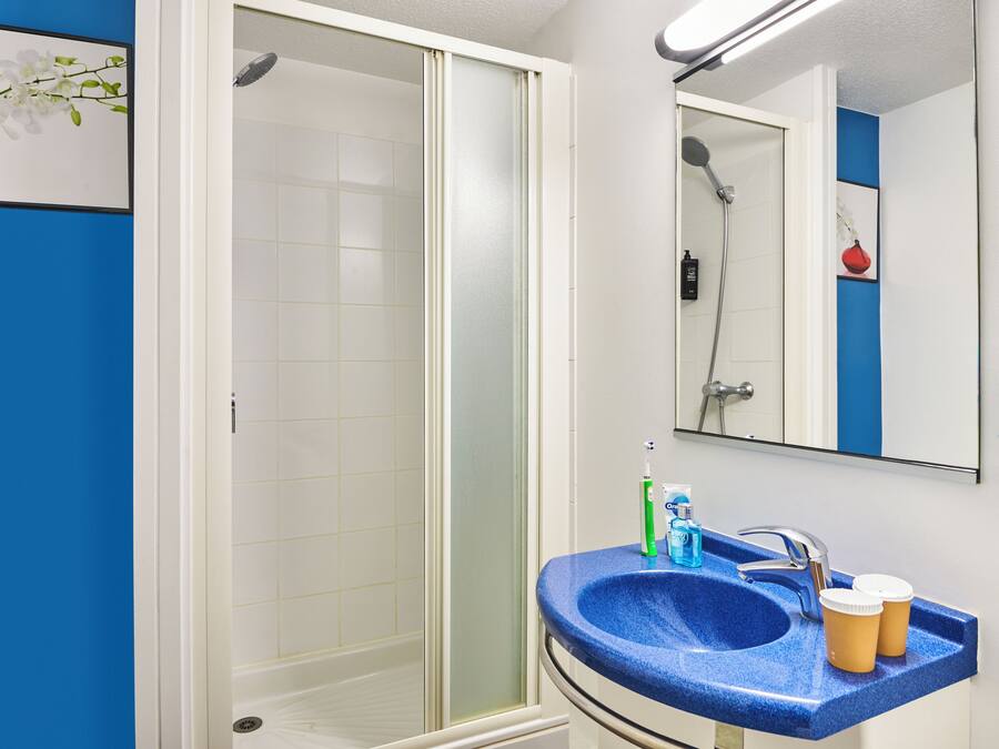 A bathroom with a blue sink, a mirror, and a shower.