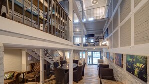 A spacious interior with a high ceiling, wooden flooring, and a mezzanine level with a staircase. - Hotel Hafen Flensburg (Flensburg)