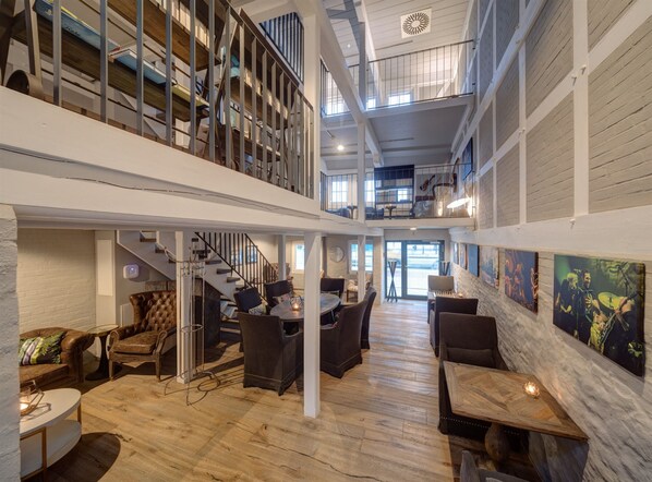A spacious interior with a high ceiling, wooden flooring, and a mezzanine level with a staircase.