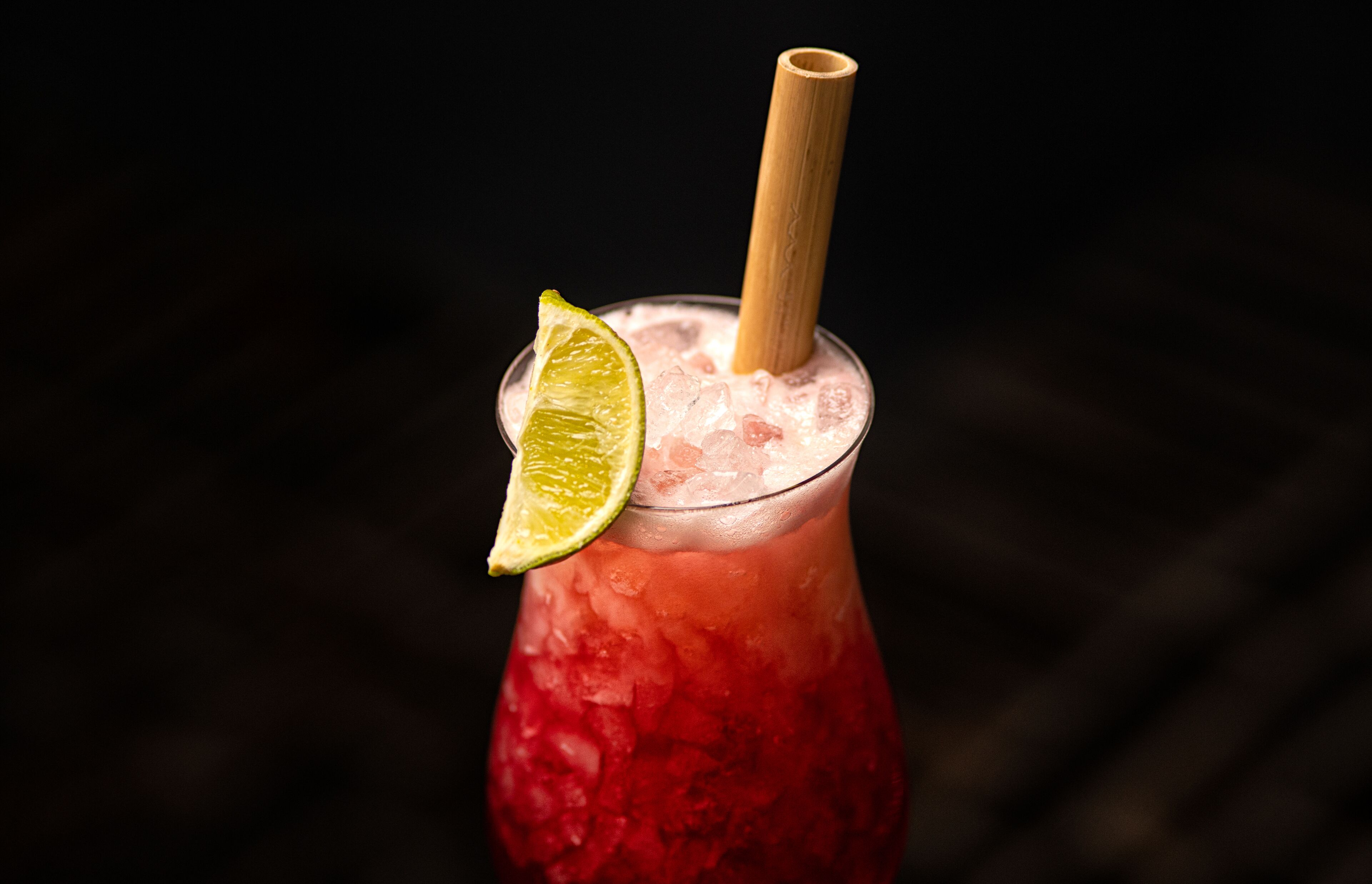 A glass with a lime wedge and a straw.