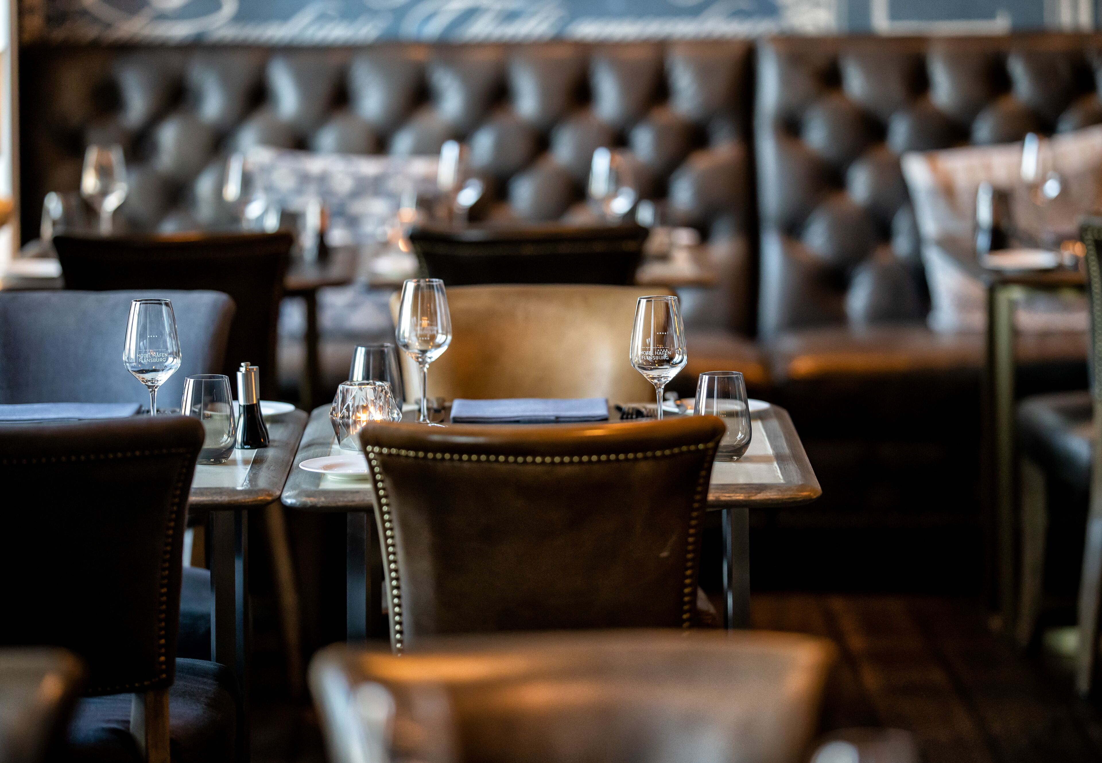 A restaurant interior with leather chairs, tables, and wine glasses.