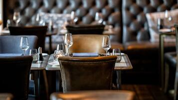 A restaurant interior with leather chairs, tables, and wine glasses.