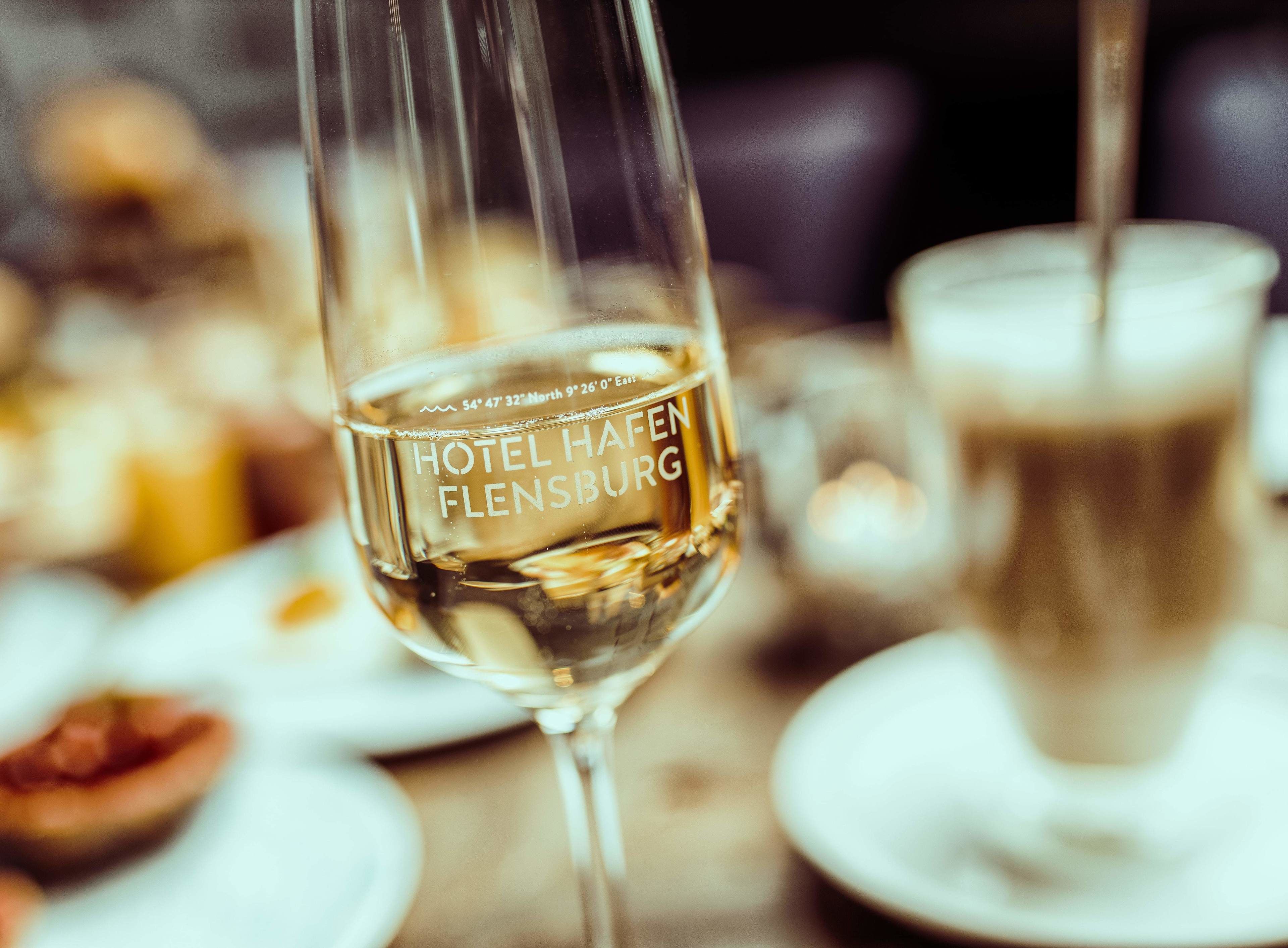 Una copa de vino blanco con el texto "HOTEL HAFEN FLENSBURG".