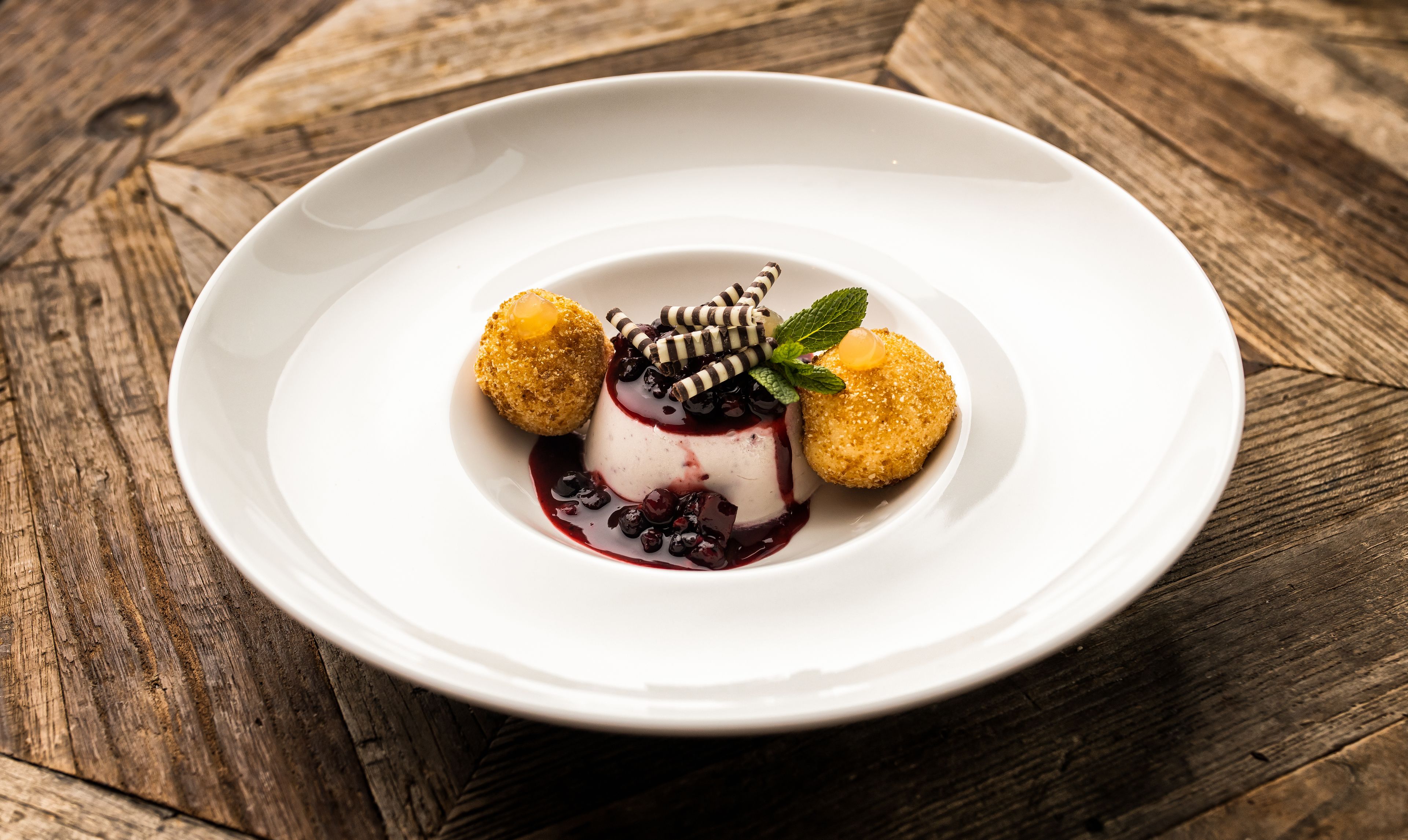 Ein Dessert auf einem weißen Teller vor rustikalem Holzhintergrund.