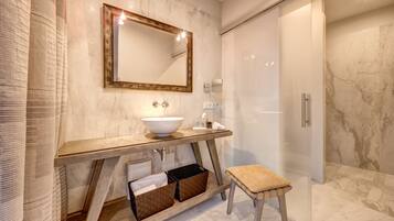 Ein modernes Badezimmer mit Marmorwaschbecken, Holzschrank und einer Duschkabine aus Glas.