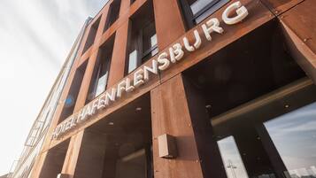 The exterior of Hotel Hafenflensburg with a modern architectural design, featuring large windows and a prominent entrance.
