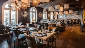 A restaurant with wooden tables, leather chairs, and hanging light fixtures. - Hotel Hafen Flensburg (Flensburg)