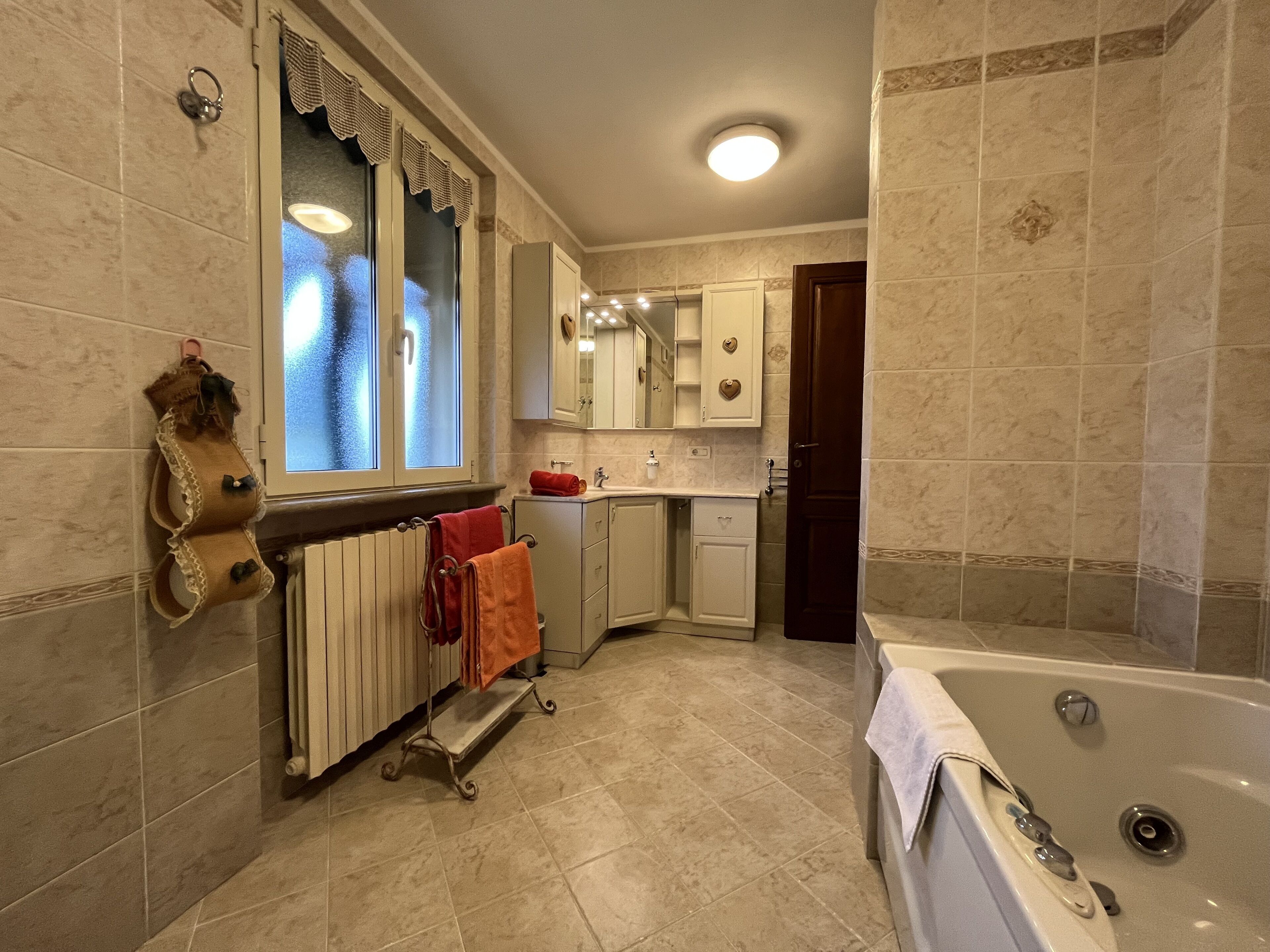 A bathroom with a bathtub, a toilet, a sink, and a window with frosted glass.
