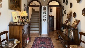 A hallway with a wooden bench, a patterned rug, and a staircase. - Cascina Folletto (Pozzolo Formigaro)