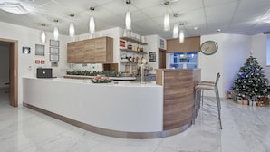 A modern kitchen with a central island, pendant lighting, a clock, and a decorated Christmas tree. - Apart Hotel Akropolis (Karlovy Vary)