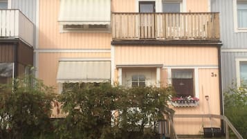 Un edificio residenziale su due piani con un balcone, un'entrata principale e un piccolo giardino.