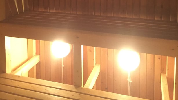 Un interior de madera con techo inclinado y dos luminarias visibles.