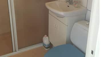 Un bagno con un lavandino bianco, un water blu e una bottiglia di gel disinfettante a pavimento.