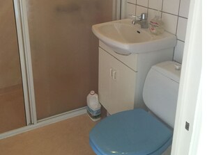 A bathroom with a white sink, a blue toilet, and a bottle of hand sanitizer on the floor.