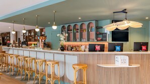 A bar area with stools, a counter, and a variety of bottles. - ibis budget Marne la Vallée Val d'Europe (Montevrain)
