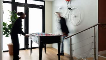 Een kamer met een tafelvoetbaltafel, een aan de muur bevestigde fiets en een trap.