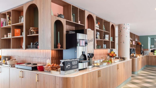 A modern kitchen with wooden cabinetry, a coffee machine, and a fruit bowl. - ibis budget Marne la Vallée Val d'Europe (Montevrain)