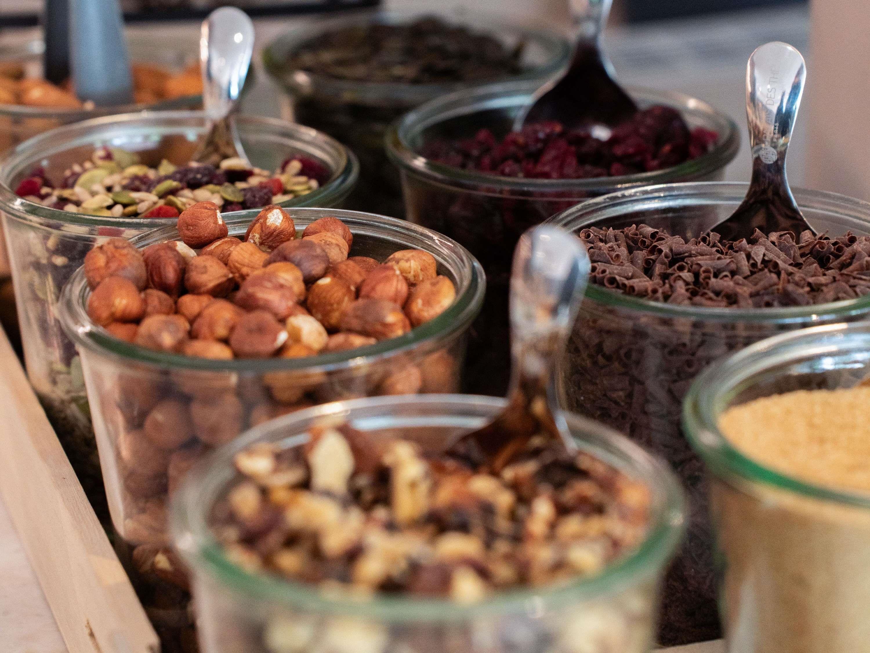 Multiple glass jars containing various nuts and dried fruits.