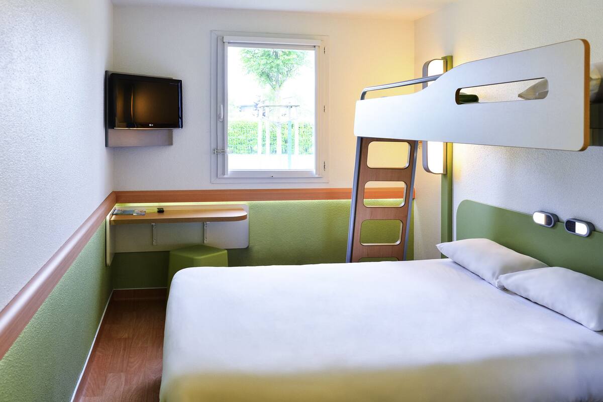 A bunk bed room with a desk and a television.