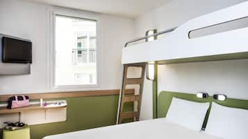 Habitación con literas, televisión, ventana, escalera y una mesita con una bolsa y zapatos.