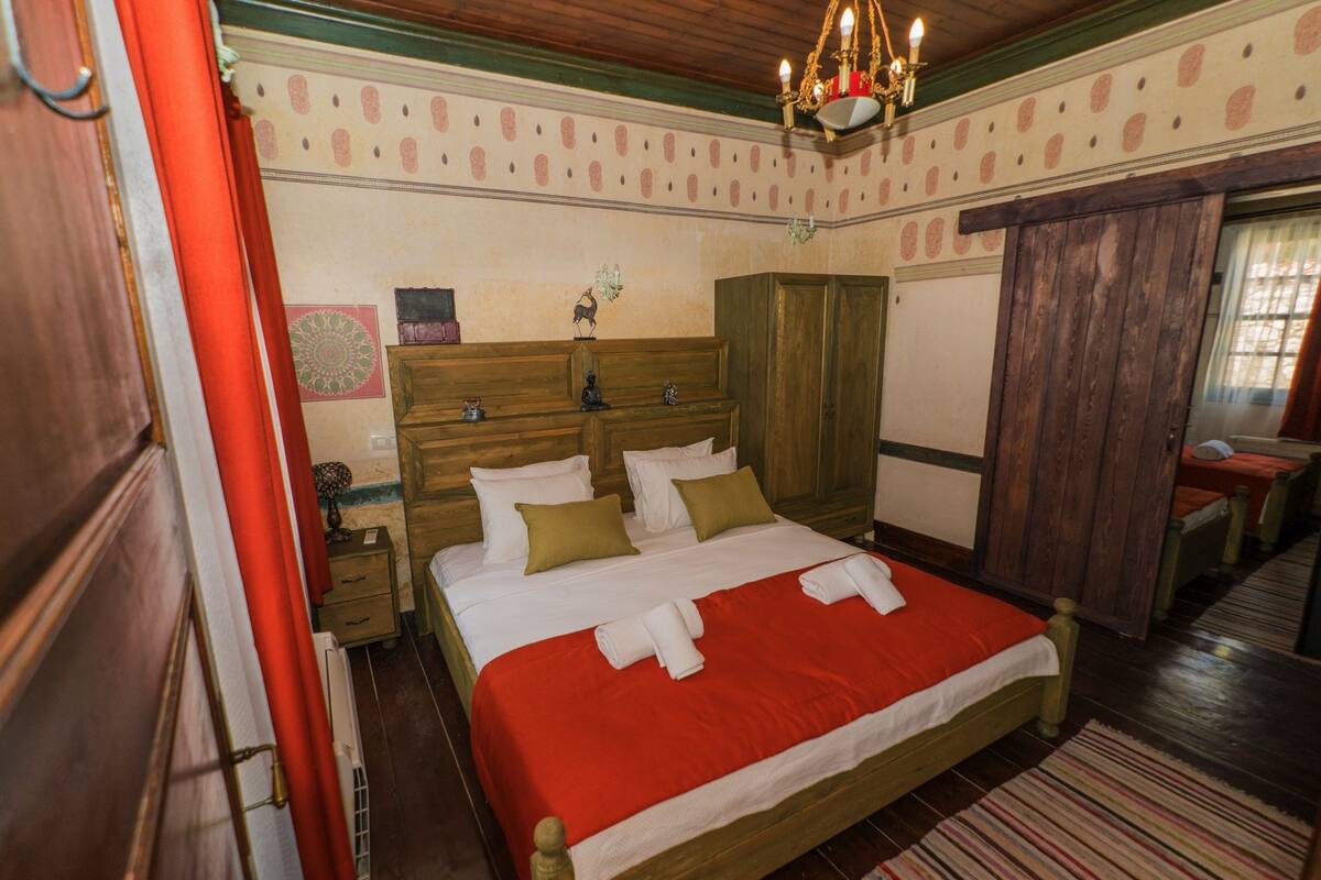 Un dormitorio con una cama de madera, una colcha roja y una araña.