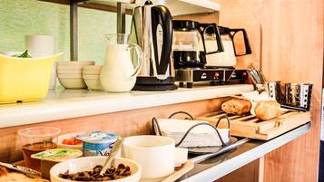 A breakfast bar with various food items, a coffee maker, and a kettle.