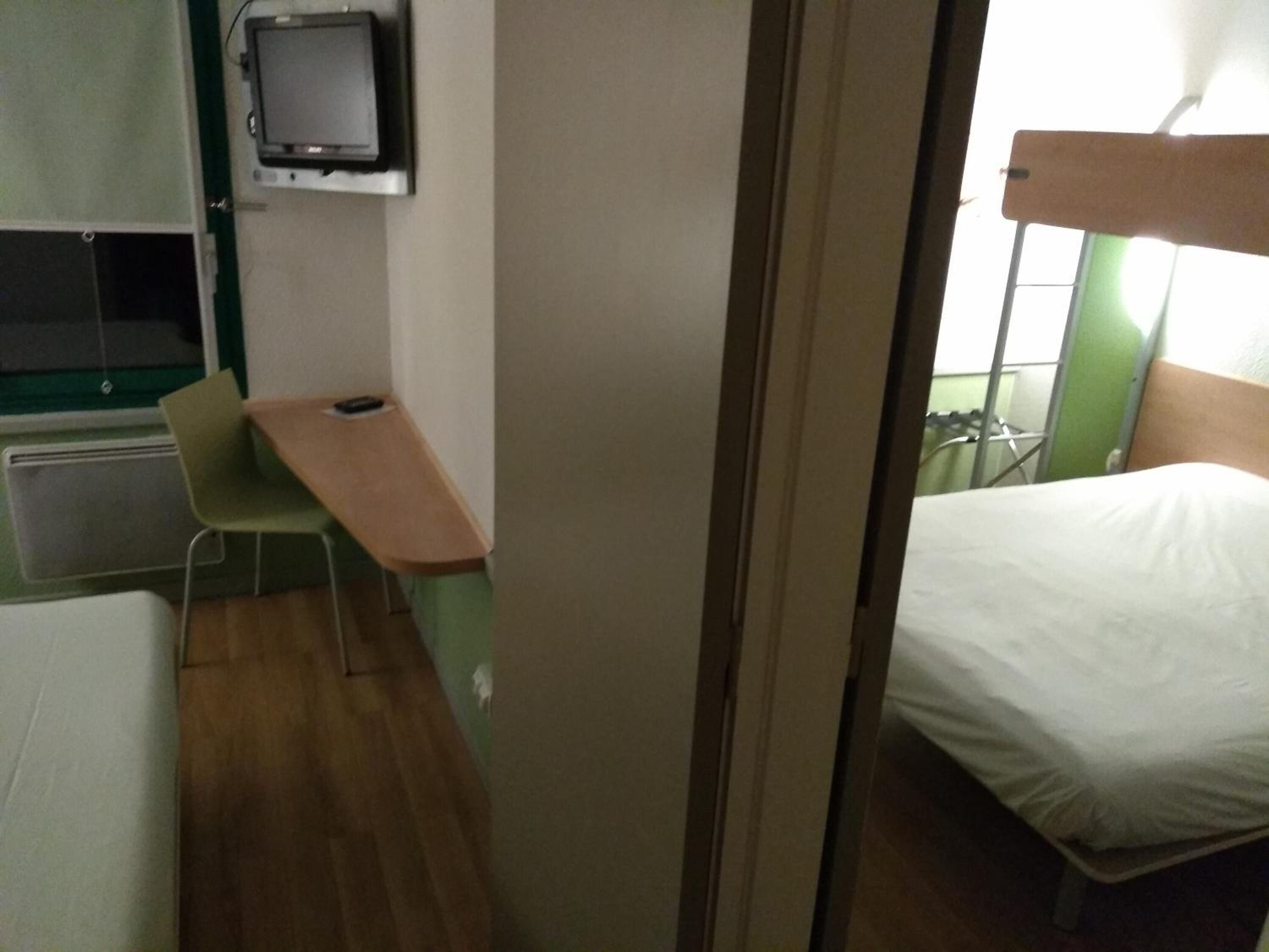 A small room with a bed, a desk, and a television.