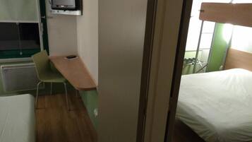 A small room with a bed, a desk, and a television.