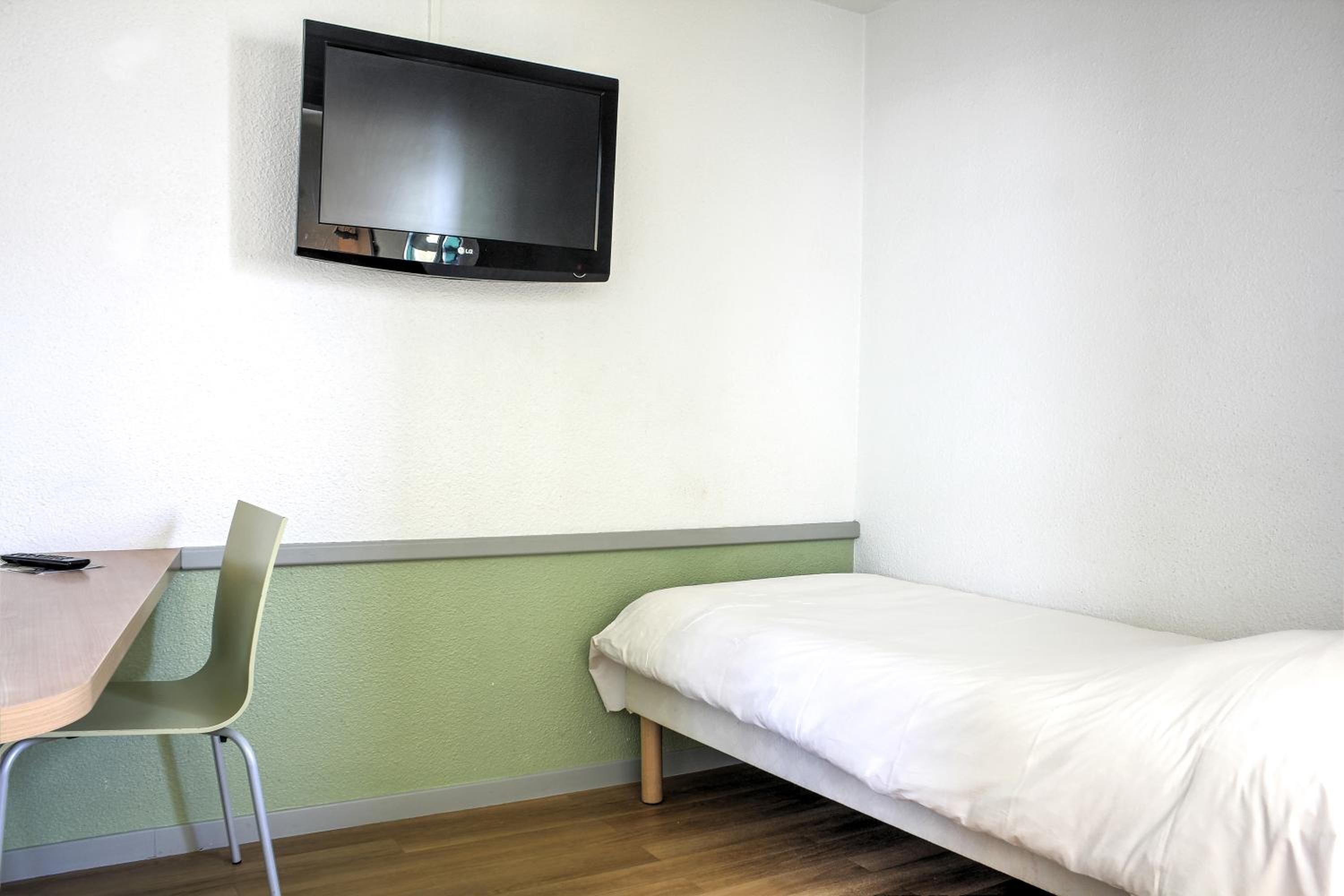 Una habitación con cama, escritorio y silla.