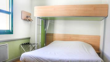 Una cama litera con cabecera de madera, escalera metálica y colchón blanco.